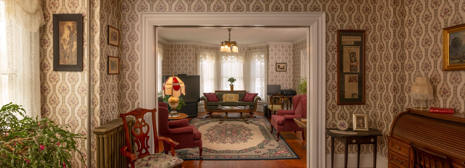 Double parlor with VIctorian decor, huge Christmas cactus on the left