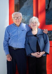 Nick and Susan standing in front of the red front doors