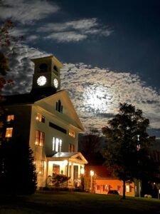 Neighboring Whitcomb Hall, shown at night with light behind the clouds, photo by Ira Asher
